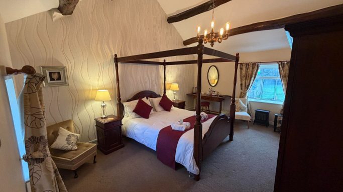 A spacious bedroom with a four-poster bed, elegant furnishings, and soft lighting.